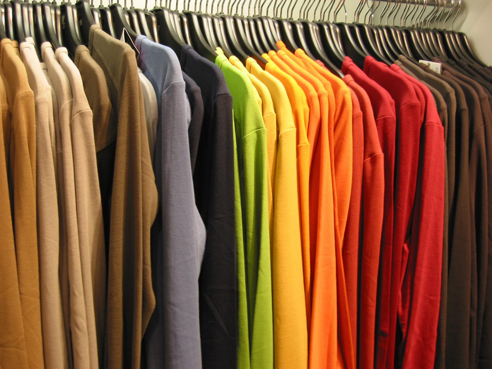 shirts hanging in a closet organized by color